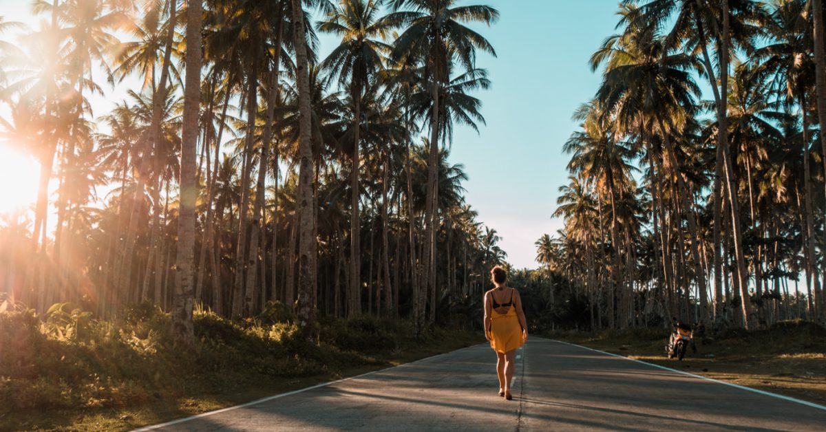 Julia auf der Straße zwischen Palmen auf Siargao, Philippinen